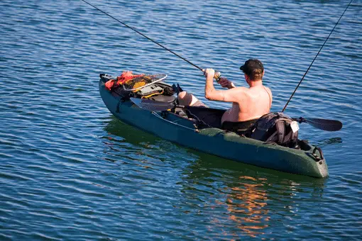 shirtless fisherman kayak fishing on smooth waters