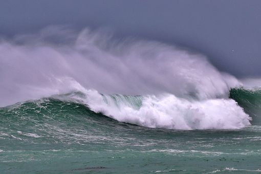 wave crashing close to rocky shoreline