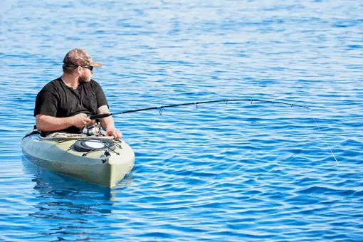angler fishing from kayak in clear blue water