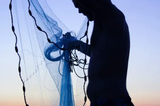 fisherman untangling a fishing net at dawn