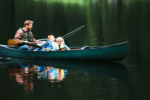 father and two children fishing from a canoe 