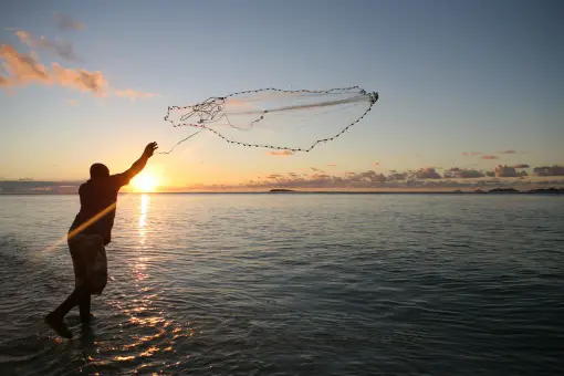 angler throwing a fishing net in the early morning