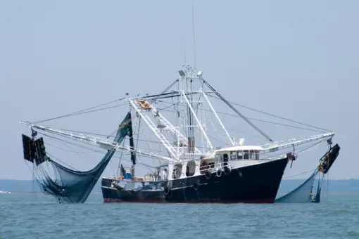 fishing trawler dropping nets in ocean
