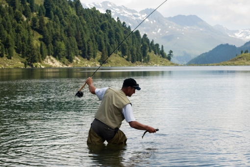 fly fisherman releases catch in a lake