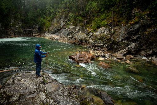 a man fly fishing a river from boulders 