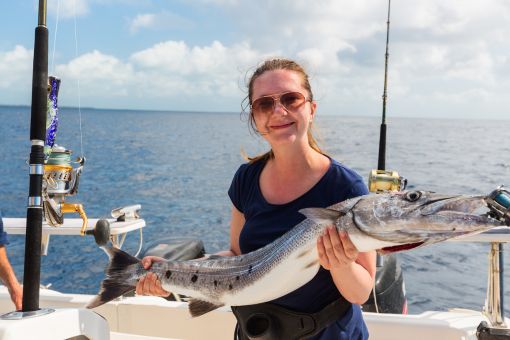 happy female angler holding a barracuda fish
