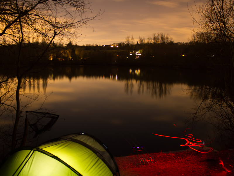 tent and fishing setup at night beside a river