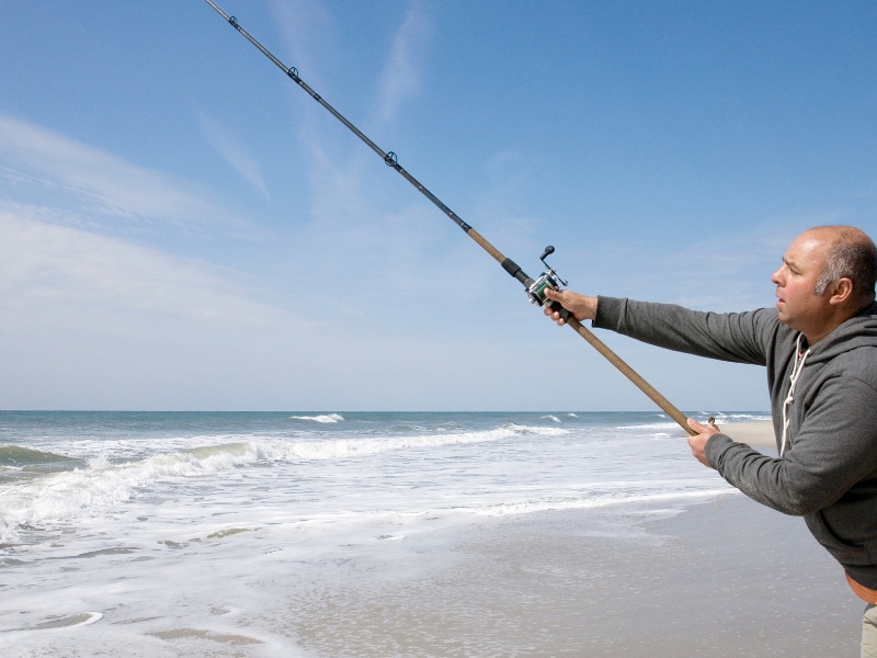 angler casts his surf rod from shore