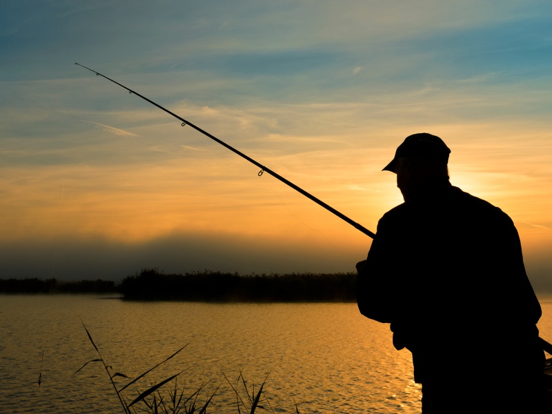 man fishing a lake at dawn