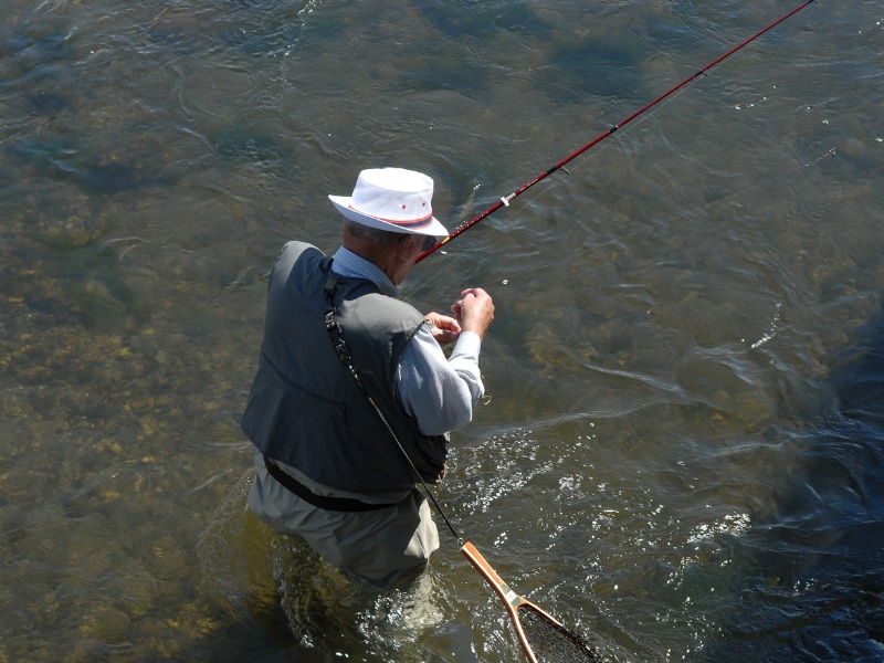 older man in waders river fishing baiting his line