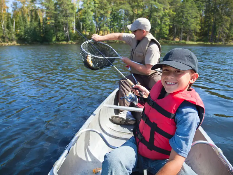 father and son catch a fish from a canoe