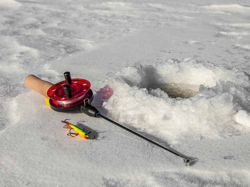 ice fishing rod next to fishing hole