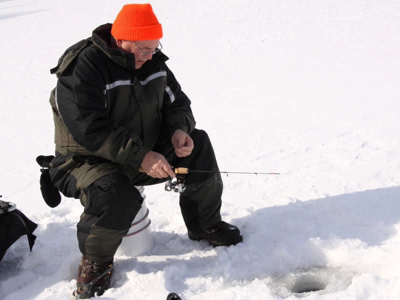 older angler ice fishing on a sunny day